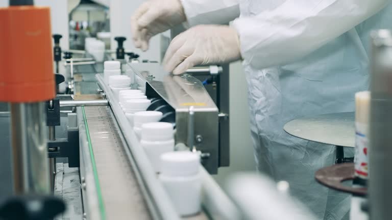 factory worker is regulating a conveyor with pill tubs. 4k